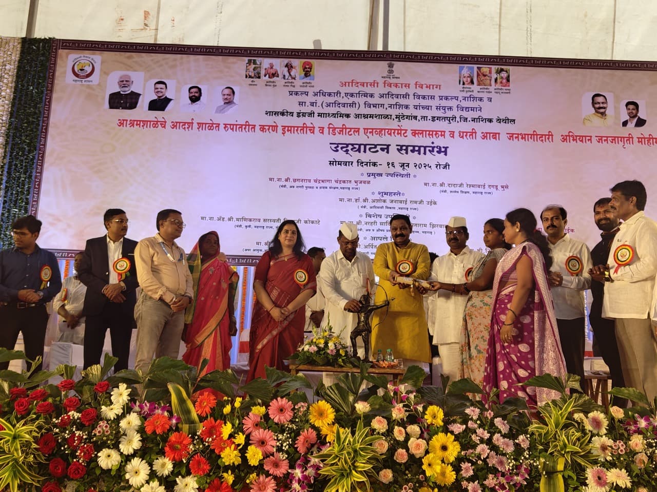 मुंडेगांव, ता. इगतपुरी येथील शासकीय इंग्रजी आश्रमशाळेच्या उद्घाटन समारंभात व्यासपीठावर रांगेत उभे सुमारे चौदा मान्यवर; समोर एकलव्याचा कांस्य पुतळा आणि मागील फलकावर १६ जून २०२५ ही तारीख व उपस्थित मंत्र्यांची नावे